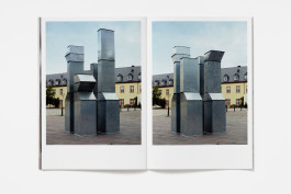 This image shows an open book, revealing two distinct full-page photographs. The left page presents an abstract, close-up image dominated by a bold, bright red curved shape that cuts vertically through the frame. This red shape contrasts sharply with a dark, reflective, possibly metallic background that shows streaks or textures. An open book displaying two photographs of Charlotte Posenenske's modular sculptures. Each photo shows a different arrangement of the same gray metallic, duct-like forms in an outdoor plaza in front of a building. 