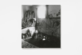 A book cover for Ishbel Myerscough: Grief, Longing and Love, showing a black and white photograph of a cluttered room with a bed, chairs, and stacked artworks. 